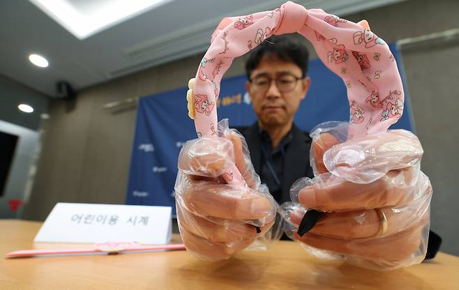 지난 16일 서울시청에서 박상진 소비자보호팀장이 인체발암 가능 물질이 검출된 해외직구 어린이용 머리띠와 시계를 들어 보이고 있다. [연합]