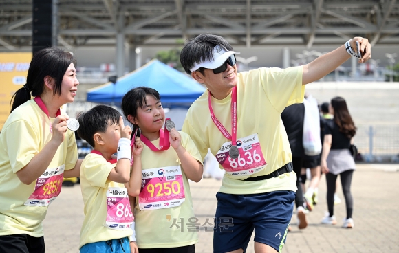 한 가족이 각자 완주 메달을 목에 걸고 미소 지으며 기념 사진을 남기고 있다. 오장환 기자