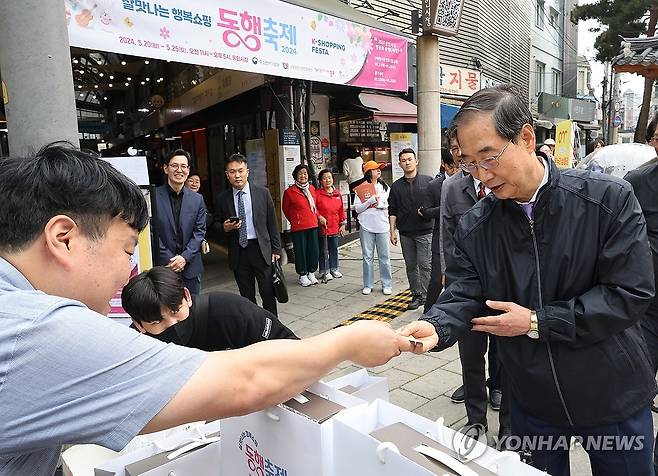 통인시장 사은행사 참가한 한덕수 총리 (서울=연합뉴스) 최재구 기자 = 한덕수 국무총리가 20일 서울 종로구 통인시장을 방문해 상인들을 격려하고 구매 영수증으로 사은행사에 참여하고 있다. 2024.5.20