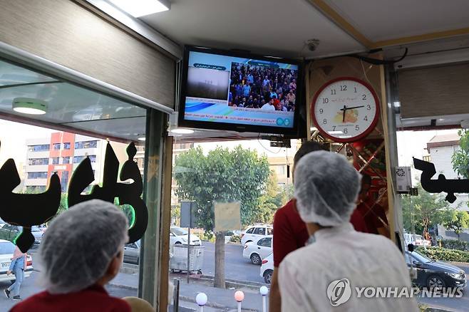 (테헤란 AFP=연합뉴스) 20일(현지시간) 이란 테헤란의 한 식당 직원들이 라이시 대통령 사망 속보를 TV로 지켜보고 있다. 2024.5.20