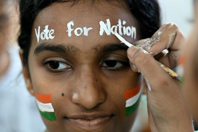 인도 뭄바이에서 한 인도 여성이 선거 직전인 지난달 17일 얼굴에 인도 국기 문양과 함께 문구를 적어 넣으며 투표를 독려하고 있다. 뭄바이=AFP 연합뉴스