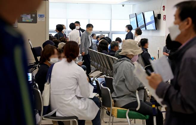의정 갈등이 계속되는 가운데 22일 서울의 한 대학병원 진료실 앞에서 의료진이 대기 중인 환자에게 다가가 진료를 보고 있다. 연합뉴스