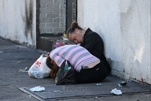 거리의 한 남성과 여성이 마약에 취해 등이 굽은 채 멈춰 있다. 이들은 최소 20분 이상 같은 자세를 보였다.