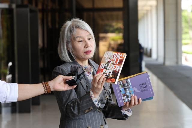 권성희 변호사가 지난 21일 오후 윤석열 대통령 부인 김건희 여사의 '명품 가방 수수 의혹' 관련 참고인 조사를 위해 서울 서초구 서울중앙지방검찰청에 출석하기 앞서 윤 대통령 내외가 살던 아크로비스타 분리수거장에서 주웠다고 주장하는 책을 취재진에게 보여주고 있다. 연합뉴스