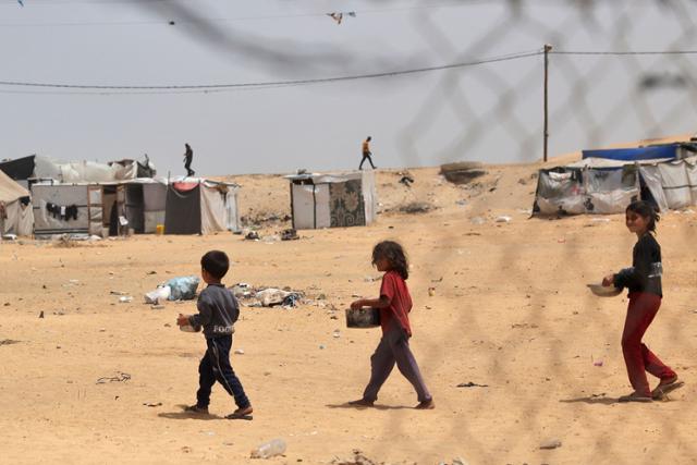 팔레스타인 어린이들이 지난 19일 가자지구 최남단 도시 라파에서 구호단체로부터 식량을 배급받고 이동하고 있다. 라파=AFP 연합뉴스