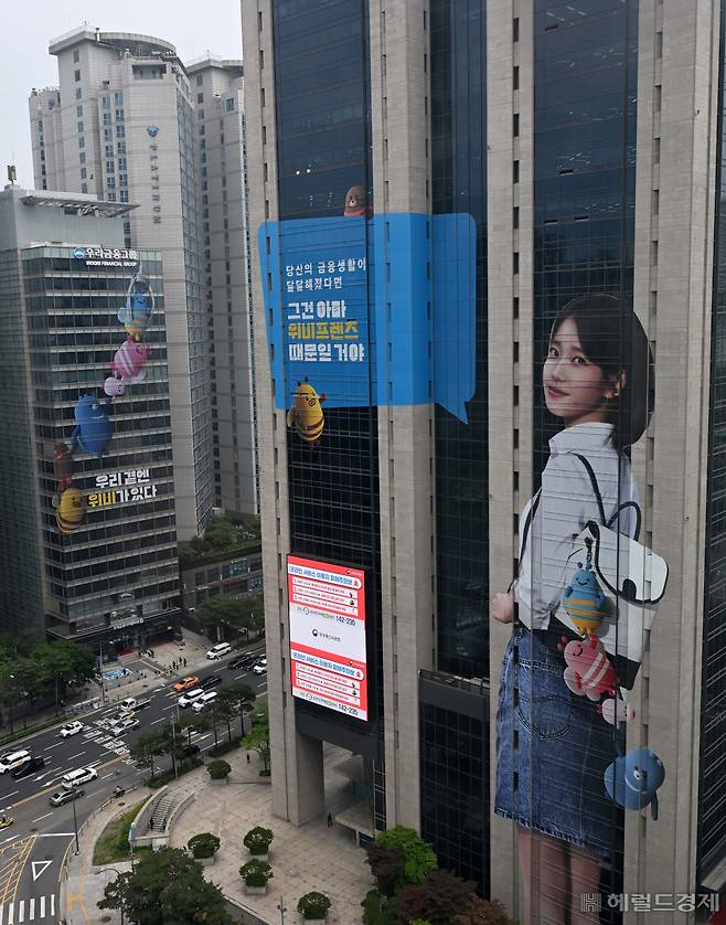 우리금융은 24일 본점 건물 외관 1층부터 16층까지 광고 모델 아이유의 래핑 광고물을 설치했다. 이상섭 기자