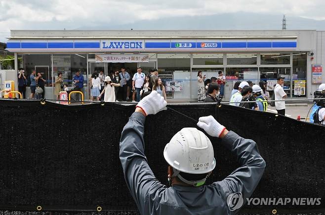 '후지산 편의점' 앞에 가림막 설치하는 인부 (후지카와구치코 AFP=연합뉴스) 21일 일본 야마나시현 후지카와구치코 마을의 후지산이 배경에 보이는 편의점 앞에 인부가 검은 가림막을 설치하고 있다. 2024.05.21 passion@yna.co.kr