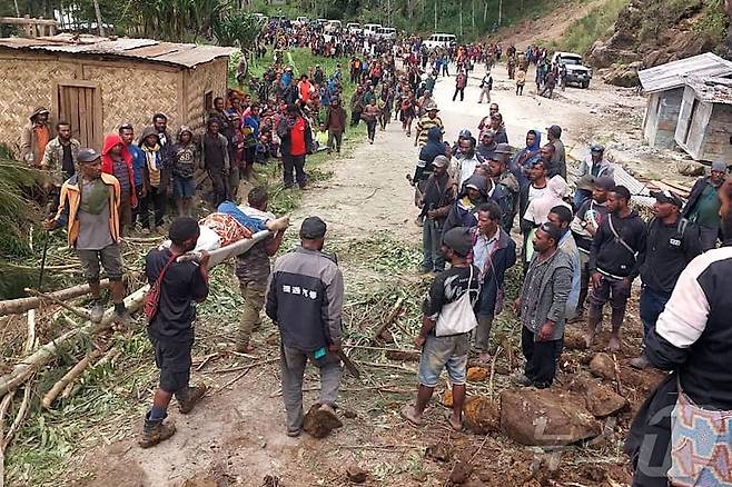 25일(현지시간) 파푸아뉴기니 엥가주(州) 마이프 물리타카 지역의 얌발리 마을에서 산사태가 발생해 현지인들이 들것으로 사상자들을 이송하고 있다. 2024.05.25/ ⓒ AFP=뉴스1 ⓒ News1 권진영 기자