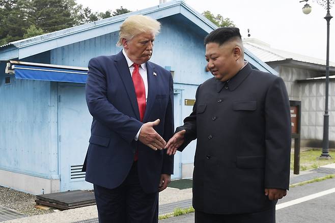 도널드 트럼프 전 미국 대통령(왼쪽)과 김정은 북한 국무위원장이 2019년 6월30일 판문점 앞뜰에서 악수를 하고 있다.   AP연합뉴스