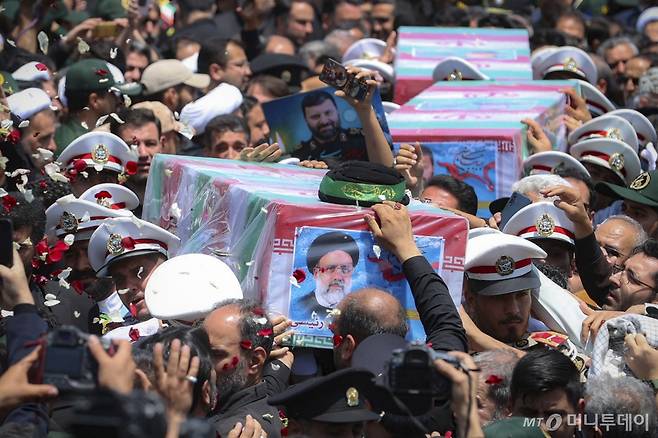 [마슈하드=AP/뉴시스] 에브라힘 라이시 이란 대통령의 고향인 이란 마슈하드에서 23일(현지시각) 이란 국기에 싸인 라이시 대통령과 헬기 추락 희생자들의 관이 운구되고 있다. 2024.05.24. /사진=민경찬