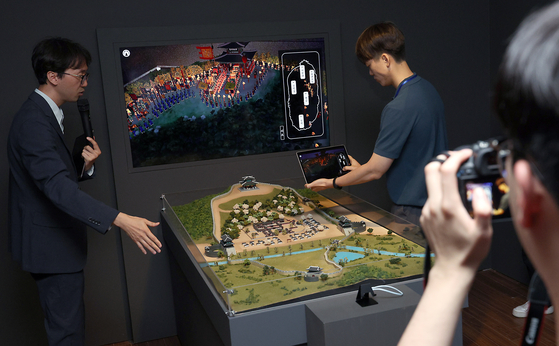 Yu Jeong-min, an associate professor at the Korea National University of Cultural Heritage, left, demonstrates an augmented reality game as part of the National Palace Museum of Korea's latest exhibition, “Hwaseong Reimagined: A Digital Dive into an 8-Day Royal Procession,″ in central Seoul on Tuesday. [NEWS1]