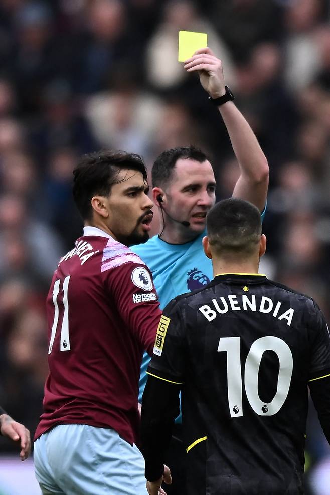 (FILES) English referee Chris Kavanagh shows a yellow card to West Ham United's Brazilian midfielder Lucas Paqueta (L) during the English Premier League football match between West Ham United and Aston Villa at the London Stadium, in London on March 12, 2023. West Ham midfielder Lucas Paqueta has been charged with alleged breaches of Football Association betting rules after a probe into claims the Brazilian deliberately earned yellow cards. Paqueta has been charged with four breaches of FA rules in relation to his conduct in West Ham's Premier League matches against Leicester in November 2022, Aston Villa in March 2023, Leeds in May 2023 and Bournemouth in August 2023. (Photo by Ben Stansall / AFP) / RESTRICTED TO EDITORIAL USE. No use with unauthorized audio, video, data, fixture lists, club/league logos or 'live' services. Online in-match use limited to 120 images. An additional 40 images may be used in extra time. No video emulation. Social media in-match use limited to 120 images. An additional 40 images may be used in extra time. No use in betting publications, games or single club/league/player publications. /<저작권자(c) 연합뉴스, 무단 전재-재배포, AI 학습 및 활용 금지>