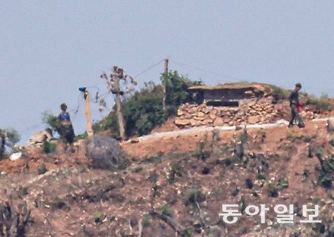 2일 오전 경기도 파주시 탄현면에서 바라본 임진강 변 북측의 한 초소 일대에서 북한군 수십 명이 철책을 설치하는 ‘대규모 진지 공사’ 장면이 포착됐다. 왼쪽 북한군의 앞에 철조망 뭉치가 보인다. 오른쪽에는 벙커처럼 보이는 건물도 보인다. 파주=이한결 기자 always@donga.com