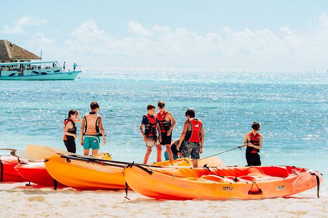 카약 탈 준비를 하는 아이들 뒤로 바다가 푸르게 물결친다