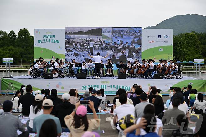 지난 25일 경기도 하남 미사경정공원에서 열린 ‘2024 상상인 피크닉데이’에서 휠체어 사용 아동 음악 재능 개발 멘토링 프로그램 ‘아카데미 상상인’에 참여한 아동들로 구성된 ‘상상휠 오케스트라’의 연주회가 진행되고 있다. (상상인그룹 제공) 2024.5.26/뉴스1