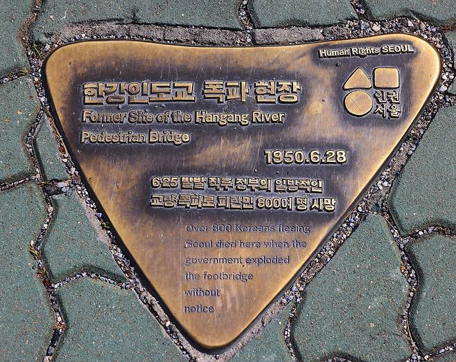 2016년 서울시가 한강대교에 설치한 동판. '일방적인 교량 폭파로 피란민 800여 명 사망'이라는 문구는 사실과 다르다. 서울시에 따르면 역삼각형 형태는 '국가 폭력'을 상징한다.