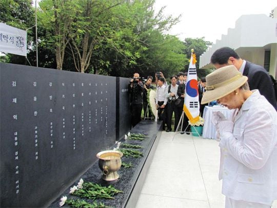 2014년 6월 6일 미얀마 양곤의 아웅산 국립묘지에서 열린 아웅산 순국 사절 추모비 제막식에서 1983년 북한의 폭탄 테러로 숨진 김재익 전 청와대 경제수석의 부인 이순자씨가 아들 김한회씨와 함께 두 손을 모아 기도하고 있다.