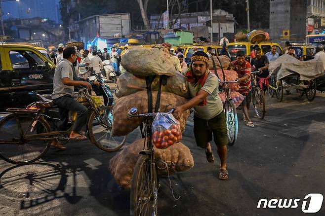 지난해 2월1일 인도 뭄바이에 있는 도매시장에서 일용직 노동자들이 자전거로 채소 포대를 옮기고 있다. 2023.02.01 ⓒ AFP=뉴스1 ⓒ News1 최종일 기자