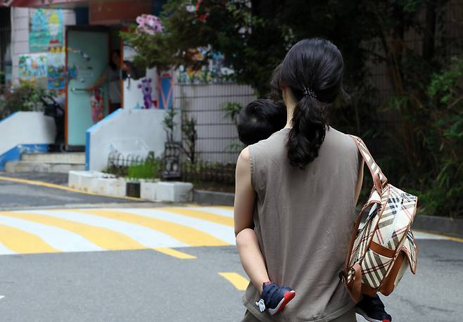 서울 한 아파트단지에서 한 엄마가 아이를 안고 어린이집으로 향하고 있다. 연합뉴스