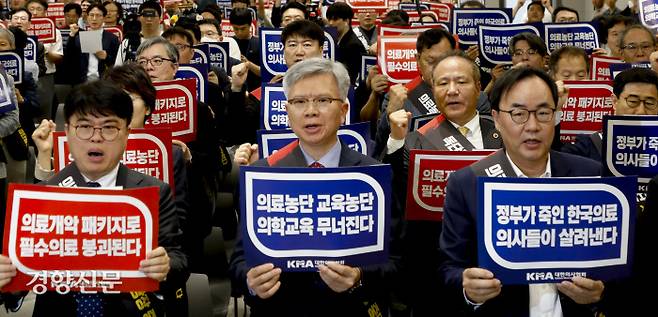 Lim Hyun-taek (L), president of the Korean Medical Association, and other medical professors, staff doctors and practitioners shout slogans condemning the government during the National Doctors‘ Congress at the Korea Medical Association Hall in Yongsan-gu, Seoul, June 9. By Jae-won Moon