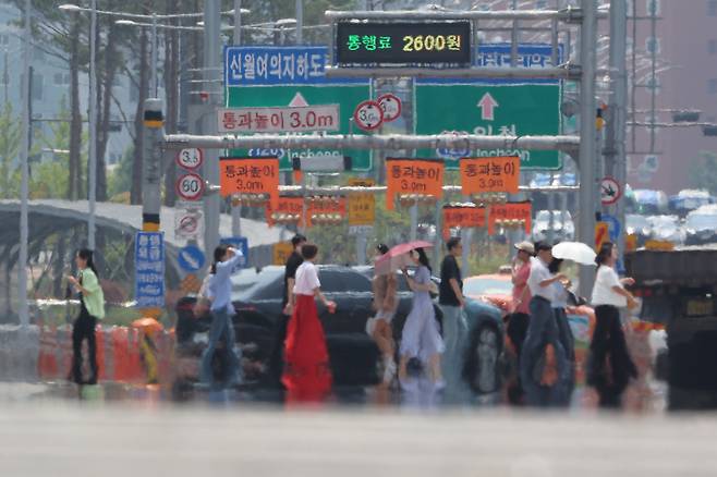 People walk amid a heat haze forming above the streets in Yeouido, western Seoul, Monday. (Yonhap)