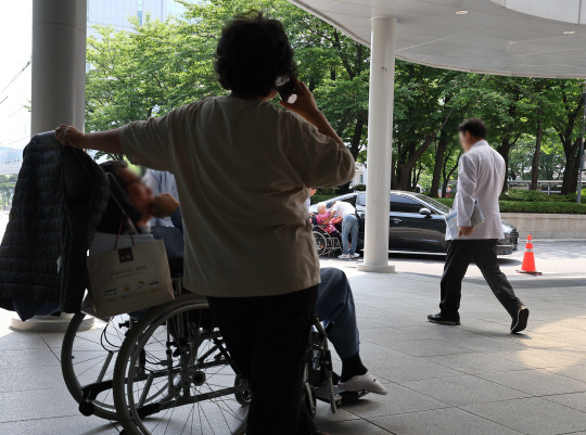 대한의사협회와 의사단체가 오는 18일부터 전면 휴진을 예고한 가운데 12일 오후 서울의 한 대학 병원에서 한 의사가 환자 앞을 지나고 있다.연합뉴스