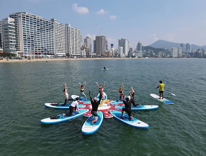 지난 2021년 6월 27일 부산 수영구 광안리해수욕장에서 시민들이 '크레이지서퍼스'에서 진행하는 요가 체험 프로그램인 '썹요가'에 참여해 SUP(Stand Up paddle)보드 위에서 균형을 잡고 있다. 해상 위에 떠 있는 도킹보드에 SUP보드를 고정시켜서 초보자도 적응훈련을 거치면 최대 8인까지 체험할 수 있는 '썹요가'는 일반 매트요가에 비해 2~3배 칼로리소모를 소모하고 색다른 요가 클래스를 찾는 사람들이 주로 찾고 있다. /김동환 기자