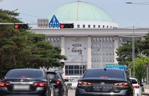 여야가 상임위원회를 배분하는 원 구성 문제를 두고 강 대 강 대치를 이어가는 가운데 국회의사당 앞 교통신호등 너머로 22대 국회 개원 축하 현수막이 보인다.  [연합뉴스]