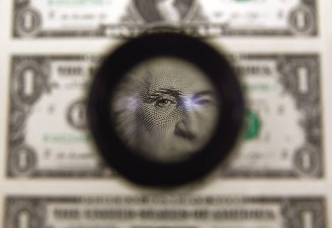 미국 재무부 산하 조폐국(BEP)에서 인쇄된 1달러 지폐를 검사하기 위해 돋보기를 사용하고 있다.