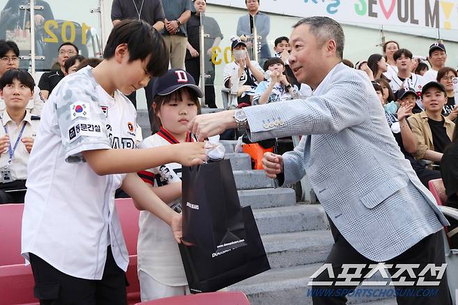 박정원 두산그룹 회장이 김예준 군(금일 시구자)과 허소윤 양(박현숙 회장 딸)에게 응원배트, 모자 등 기념 선물을 전달하는 모습. <사진제공=두산 베어스>