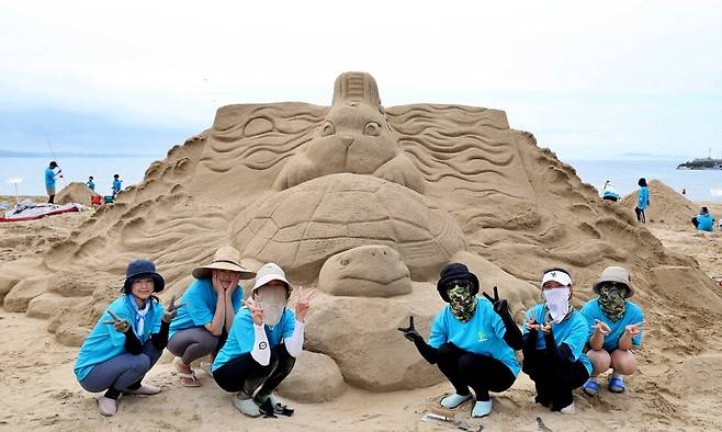 지난해 태안 모래조각 페스티벌에 참가한 한 일반인팀이 ‘토끼와 거북이’를 완성하고 기념사진을 찍고 있다. 태안군 제공