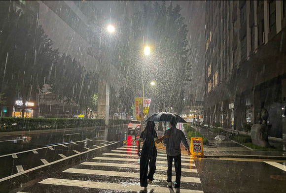 대구 남구 명덕역 인근 거리에서 두 시민이 비를 막기 위해 우산을 나눠쓰고 있다. [사진=뉴시스]