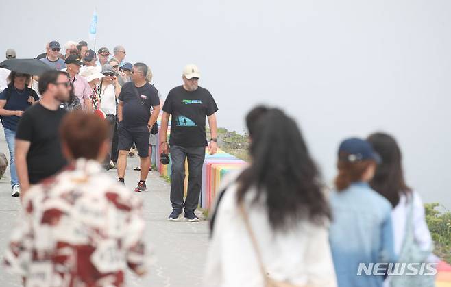 [제주=뉴시스] 우장호 기자 = 제주 해안가를 중심으로 짙은 안개가 드리워진 12일 오전 제주시 무지개해안도로를 찾은 외국인 관광객들이 산책로를 걸어가고 있다. 2024.06.12. woo1223@newsis.com