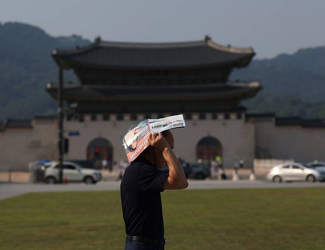 폭염 주의보가 발령된 19일 오후 서울 광화문광장을 찾은 한 시민이 광고지로 햇볕을 가리고 있다. 연합뉴스