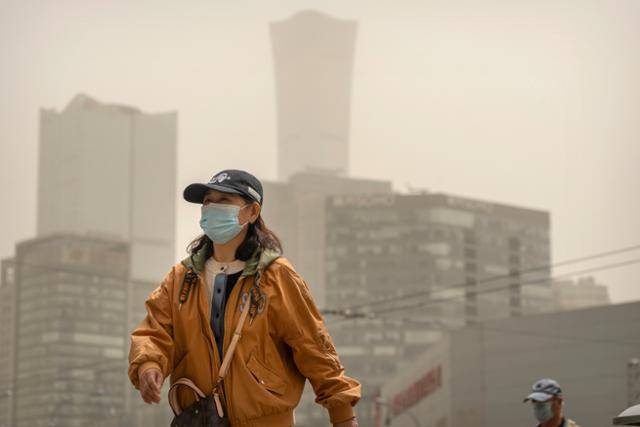 지난해 4월 25일 중국 베이징에 짙은 황사가 낀 가운데, 한 여성이 마스크를 착용하고 길을 걷고 있다. 베이징=AP 연합뉴스