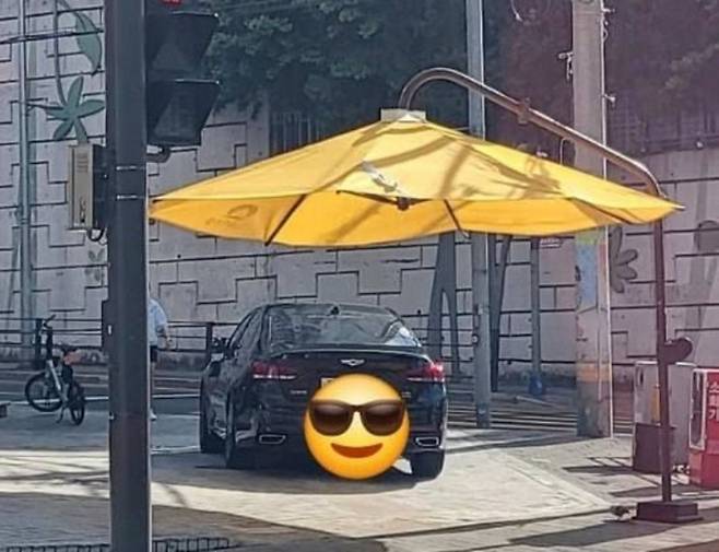 지난달 횡단보도 앞 인도에 설치된 그늘 쉼터 아래 검은색 승용차가 주차된 모습. 온라인 커뮤니티 갈무리