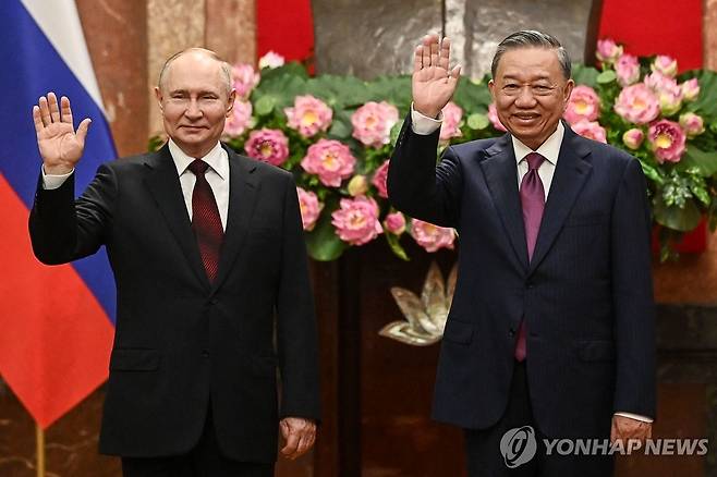 베트남 국가주석과 손 흔드는 푸틴 (하노이 AFP=연합뉴스) 베트남을 방문한 블라디미르 푸틴 러시아 대통령(왼쪽)이 20일 하노이 주석궁에서 또 럼 베트남 국가주석과 나란히 손을 흔들고 있다. 푸틴 대통령은 베트남 방문 기간에 베트남 권력 서열 1∼4위를 모두 만날 예정이다. 2024.06.20 passion@yna.co.kr