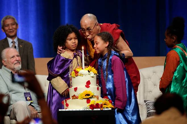 달라이 라마가 80번째 생일을 축하하는 축하장 무대 위에서 합창단 어린이들을 껴안고 함께 케이크의 촛불을 불고 있다. /AP 연합뉴스