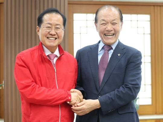지난 6월25일 대구광역시청에서 홍준표(왼쪽) 대구시장이 소속당인 국민의힘의 황우여(오른쪽) 비상대책위원장을 접견하면서 손을 잡고 기념 촬영을 하고 있다.<연합뉴스 사진>