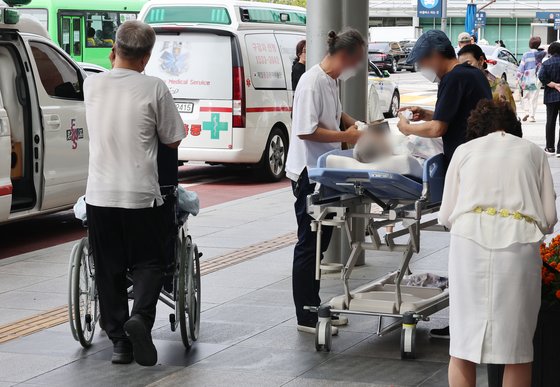지난 25일한 대형병원 앞에서 한 환자가 침상에 누운 채 대기하고 있다. 기사 이해를 돕기 위한 자료사진. 연합뉴스