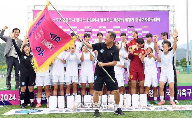 울산 현대청운중 김광석 감독(가운데)이 27일 경남 합천군 군민체육공원에서 진행된 ‘2024 스포츠 명품도시 웰니스 합천에서 펼쳐지는 제32회 여왕기 전국여자축구대회’ 중등부 충북 예성여중과 결승전에서 승리해 우승을 차지한 뒤 우승기를 흔들며 기념촬영을 하고 있다. 2024. 6. 27.  합천 | 박진업 기자 upandup@sportsseoul.com