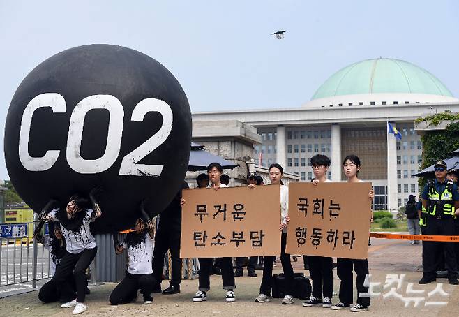 국제 환경단체 그린피스와 청년환경단체 회원들이 세계 환경의 날 국회 앞에서 기후위기 대응을 촉구하는 '탄소(CO2)의 짐' 퍼포먼스를 하고 있다. 이들은 대형 탄소 조형물을 짊어진 채 온몸에 뚝뚝 떨어지는 화석연료의 피해를 표현하고, 계속 증가하는 탄소 배출의 심각성을 표현했다. 황진환 기자