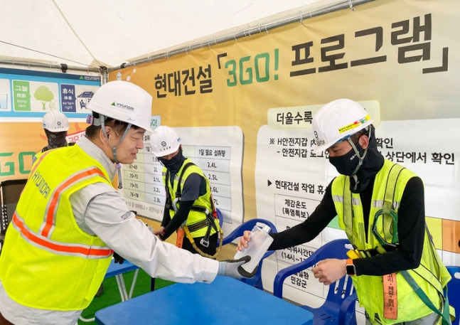 황준하 현대건설 CSO(왼쪽)가 지난 27일 힐스테이트 회룡역 파크뷰 현장을 찾아 근로자들에게 수분 보충 음료를 제공하고 있다./사진제공=현대건설