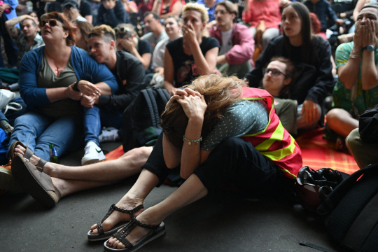좌파 연합 지지자들이 30일 프랑스 총선 출구조사 결과를 확인한 뒤 머리를 감싸쥐며 안타까워하고 있다. AFP 연합뉴스
