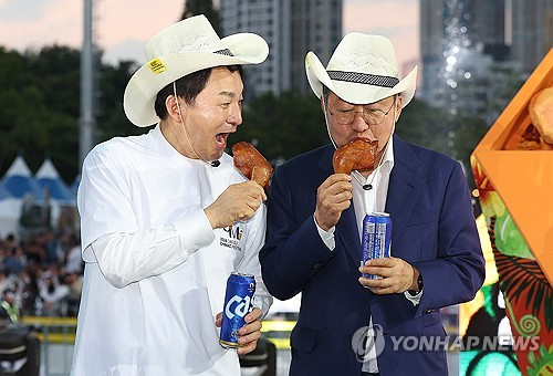 국민의힘 원희룡 당 대표 후보(왼쪽)와 홍준표 대구시장이 3일 대구 달서구 두류공원 2·28 자유광장에서 열린 '2024 대구치맥페스티벌' 개막식에서 치킨을 먹고 있다. 연합뉴스