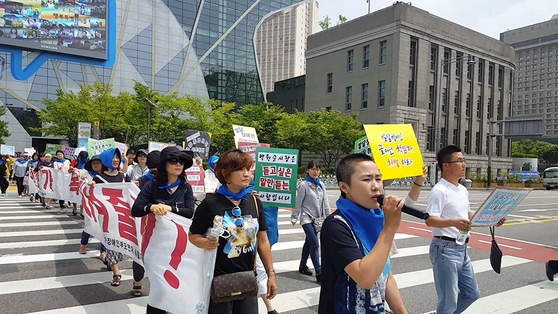 A still image from the film ″A Long Way to School″ shows families of people with disabilities rallying outside City Hall in central Seoul on April 2, 2016,is protest of the government's lowered budget for welfare for people with disabilities. [JINJIN PICTURES]