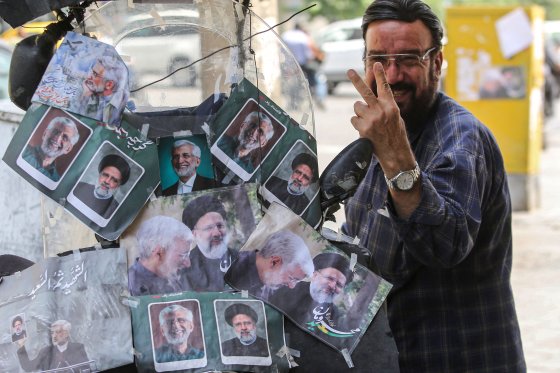 대선 결선 투표를 하루 앞둔 지난 4일 이란 테헤란에서 한 이란 시민이 결선에 나선 사이드 잘릴리 전 외교차관과 에브라힘 라이시 전 대통령의 사진이 붙은 오토바이 옆에서 미소 짓고 있다. AFP=연합뉴스