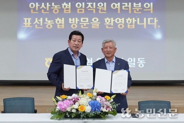 박경식 경기 안산농협 조합장(왼쪽)과 김용우 제주 서귀포 표선농협 조합장이 서명한 자매결연 협약서를 들어 보이고 있다.