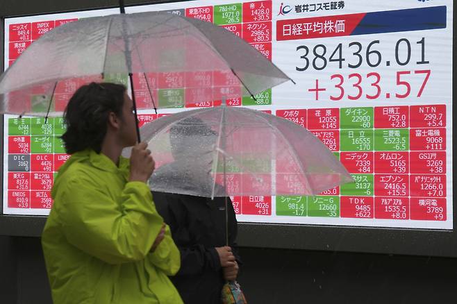한 일본 시민이 6월18일 일본 도쿄 증권거래소 앞에 있는 닛케이 평균주가지수 전광판 앞을 지나고 있다.ⓒAP Photo