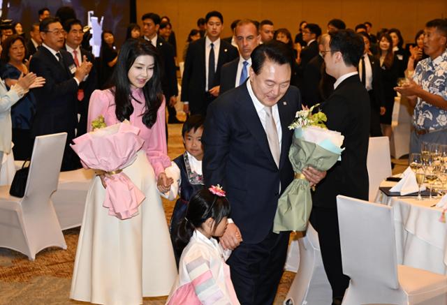 미국 하와이 호놀룰루를 방문 중인 윤석열 대통령과 부인 김건희 여사가 8일(현지 시간) 동포 만찬 간담회에 참석해 화동으로부터 꽃을 받은 후 함께 행사장으로 입장하고 있다. 호놀룰루=왕태석 선임기자